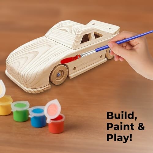 Hand painting a wooden toy car with colorful paints and brush.