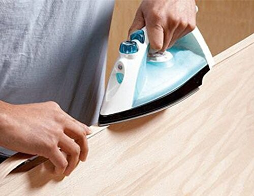 Person using an iron to apply edge banding on wood.