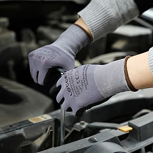 Person wearing gloves working on car engine.