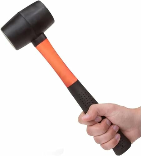 Hand holding a rubber mallet with an orange and black handle