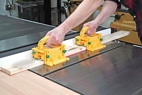 Person using safety push blocks on a table saw with wood.