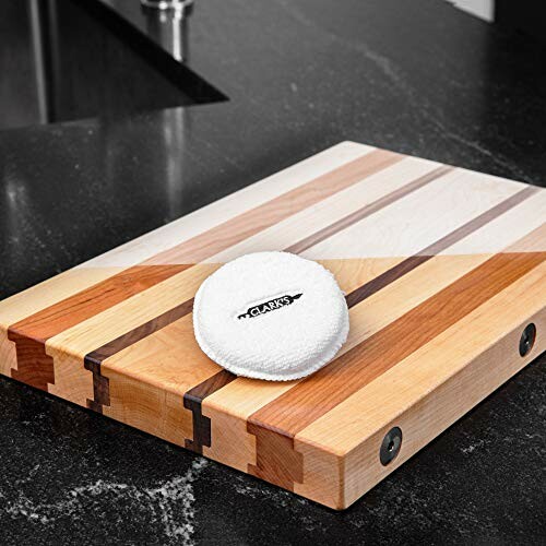 Wooden cutting board with conditioning pad on kitchen counter.